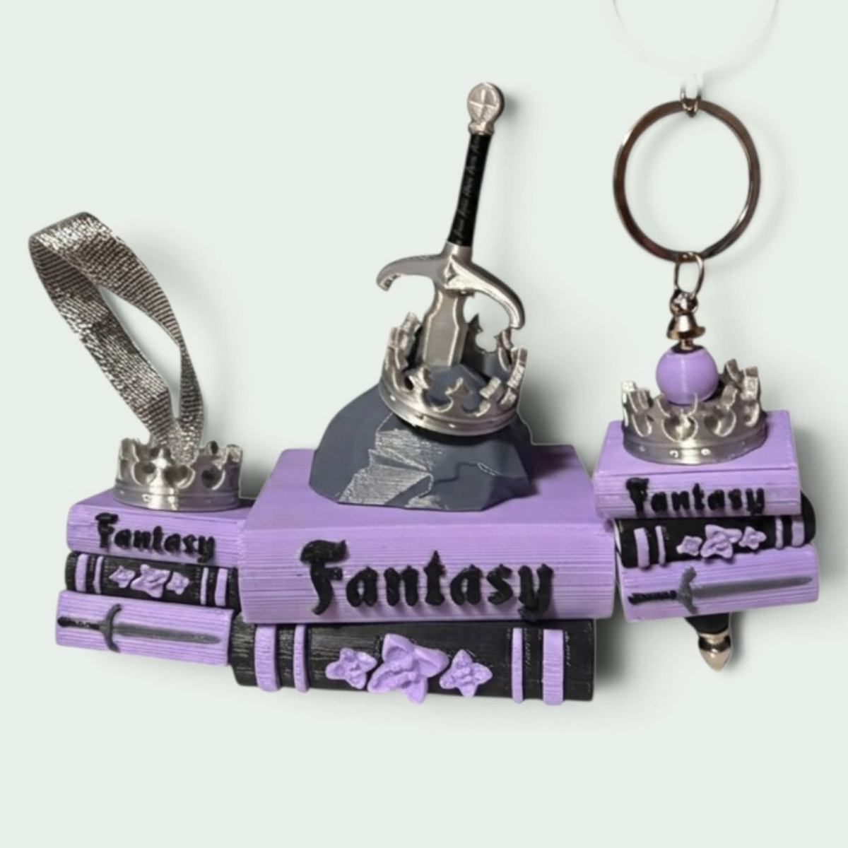 Verleihe deinem Bücherregal, deinem Schlüsselbund oder deinem Weihnachtsbaum den perfekten Fantasy-Vibe! Dieses liebevoll gestaltete "Fantasy" Book Pile mit Krone, Schwert- und Stein-Details ist ein absoluter Hingucker für alle Buchliebhaber.