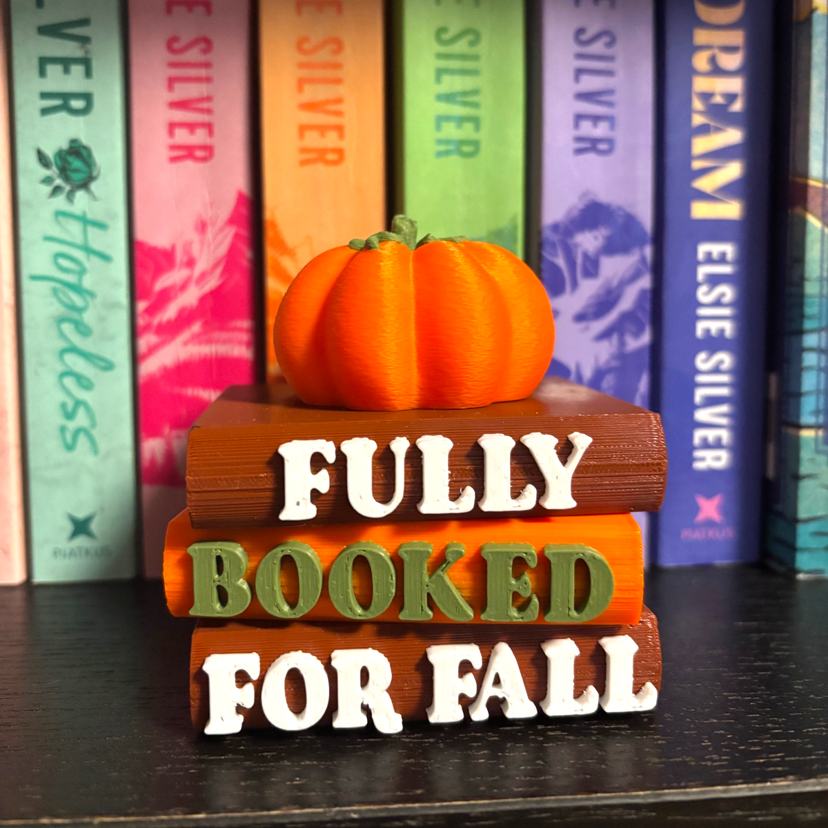 Verleihe deinem Bücherregal, deinem Schlüsselbund oder deinem Weihnachtsbaum den perfekten Herbst-Vibe! Dieses liebevoll gestaltete "Fully Booked for Fall" Book Pile mit Kürbis-Details ist ein absoluter Hingucker für alle Buchliebhaber.