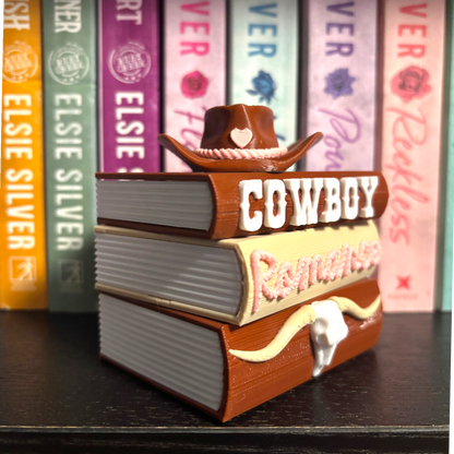 Verleihe deinem Bücherregal, deinem Schlüsselbund oder deinem Weihnachtsbaum den perfekten Romantasy-Vibe! Dieses liebevoll gestaltete "Cowboy Romance" Book Pile ist ein absoluter Hingucker für alle Buchliebhaber.