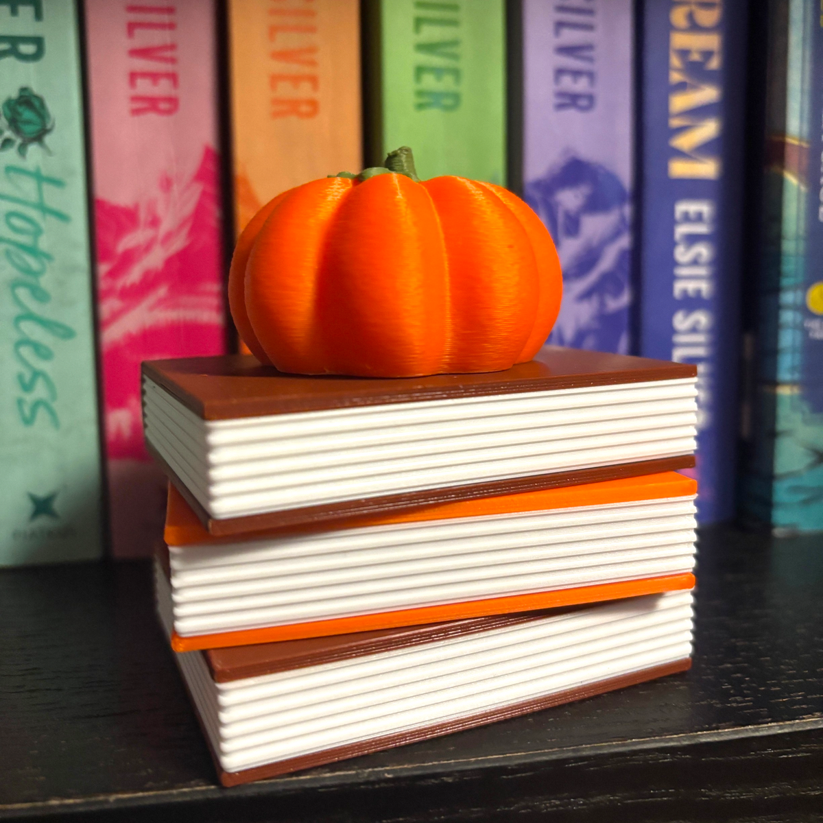 Verleihe deinem Bücherregal, deinem Schlüsselbund oder deinem Weihnachtsbaum den perfekten Herbst-Vibe! Dieses liebevoll gestaltete "Fully Booked for Fall" Book Pile mit Kürbis-Details ist ein absoluter Hingucker für alle Buchliebhaber.