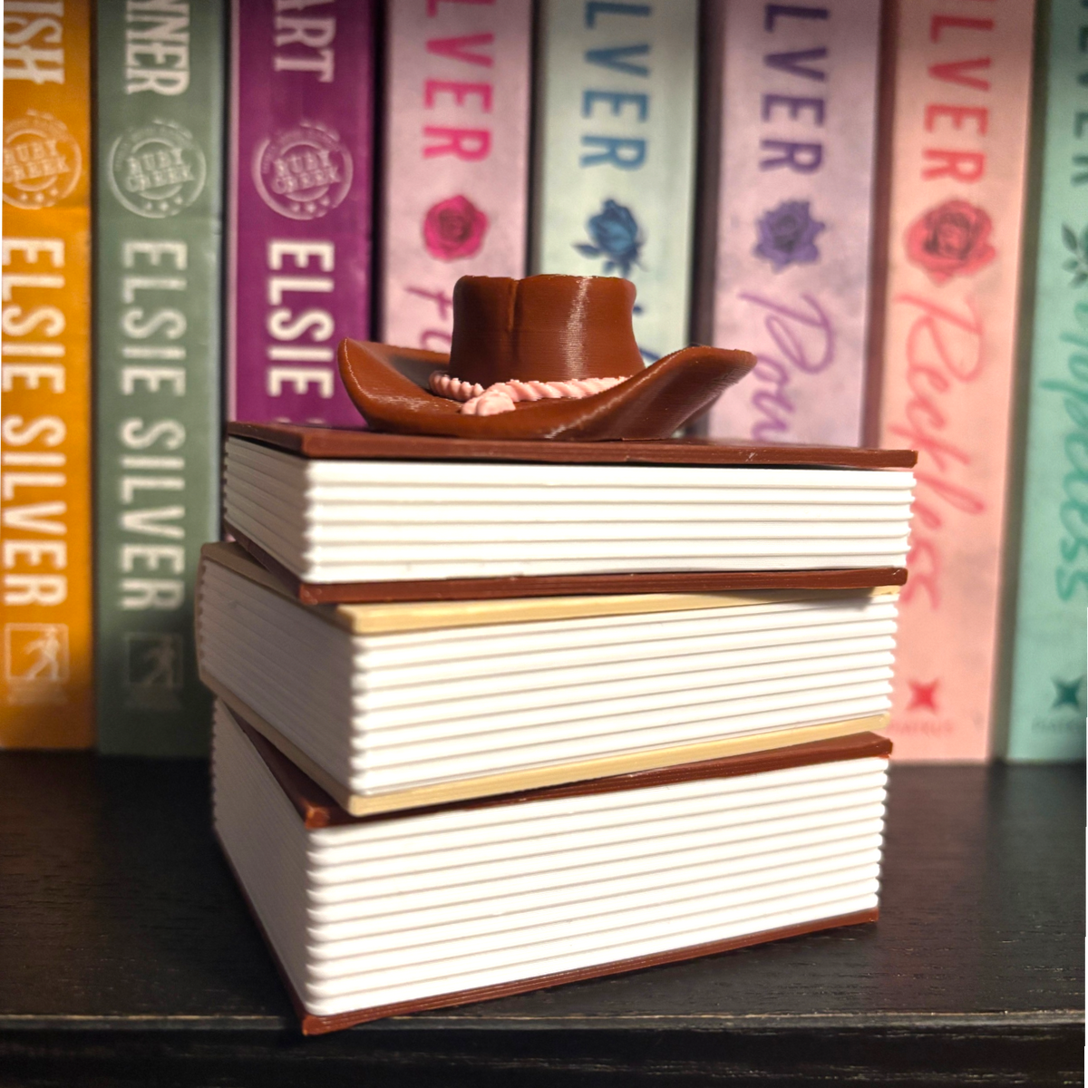 Verleihe deinem Bücherregal, deinem Schlüsselbund oder deinem Weihnachtsbaum den perfekten Romantasy-Vibe! Dieses liebevoll gestaltete "Cowboy Romance" Book Pile ist ein absoluter Hingucker für alle Buchliebhaber.