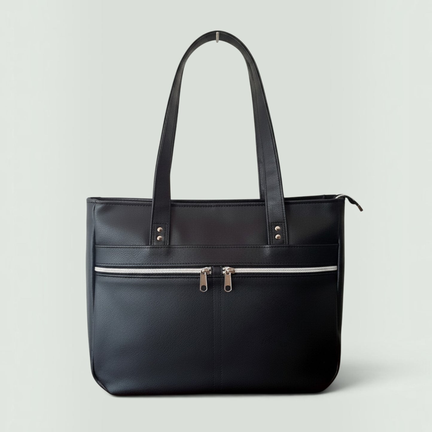 Schneckenschmiede Divina Handtasche in Schwarz mit zwei Front-Reißverschlusstaschen und Henkeln aus Kunstleder.