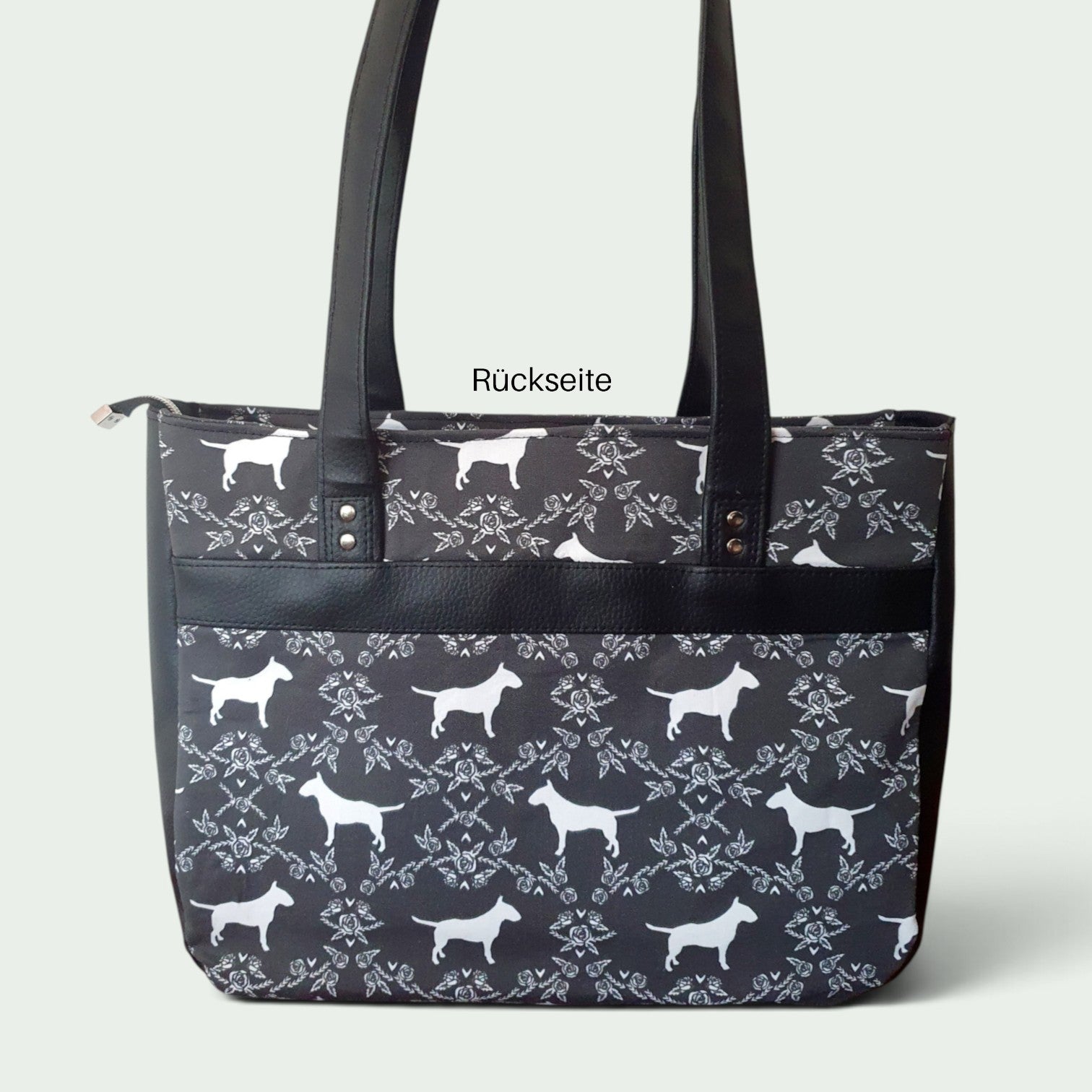 Schneckenschmiede Handtasche Divina mit schwarz-weißem Hundemuster, Kunstleder-Details und zwei Fronttaschen.