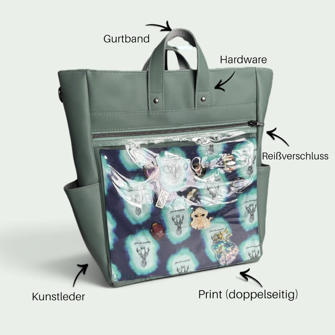 Schneckenschmiede ITA Rucksack aus grünem Kunstleder mit transparentem Frontfach zur Präsentation von Pins und Buttons
