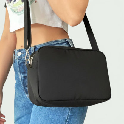 Schneckenschmiede Umhängetasche Catalina in schlichtem Schwarz mit verstellbarem Schultergurt, getragen als Crossbody.