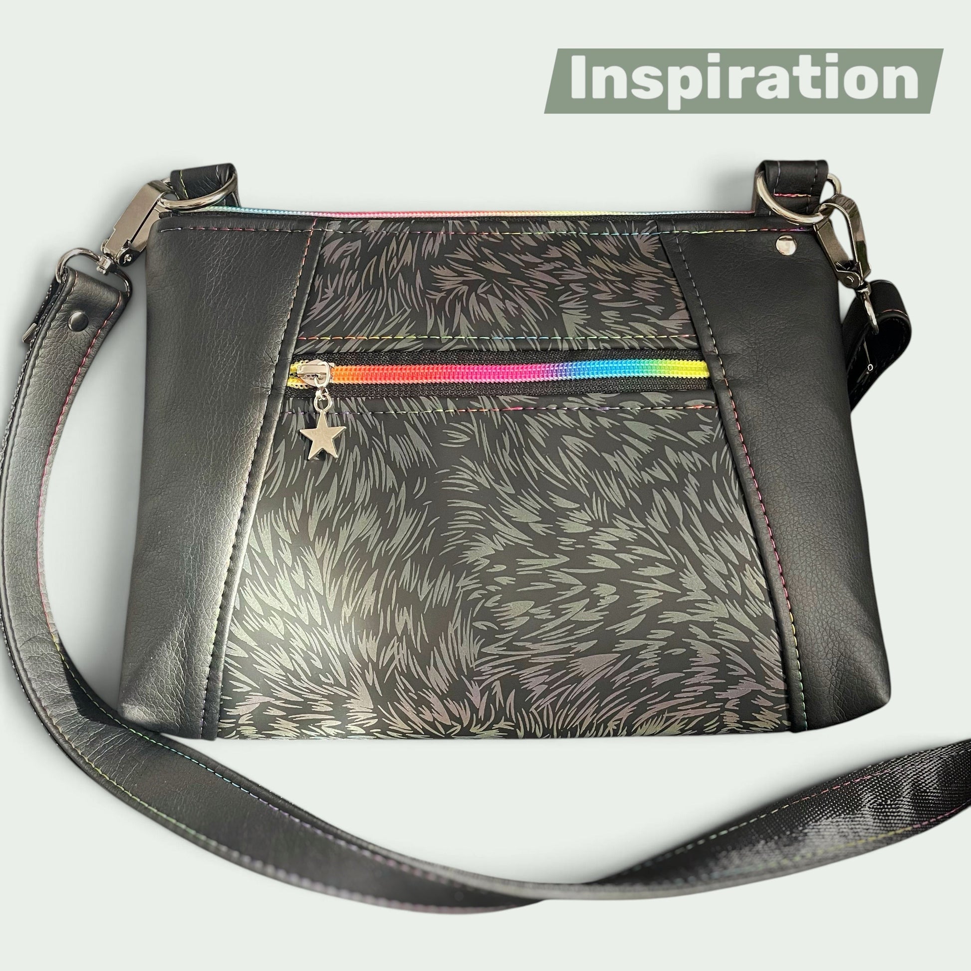 Schneckenschmiede Umhängetasche Sunshine aus schwarzem Kunstleder mit buntem Regenbogen-Reißverschluss und Stern-Anhänger