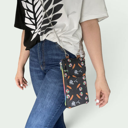 Schneckenschmiede Zip n Go Handytasche mit Anime-Print, Kartenfächern und silberner Kette als Umhängetasche getragen.